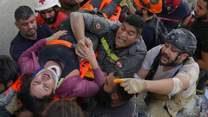 A man hugs a cat after it was pulled alive from the rubble of a building that partially collapsed in the Lebanese town of Mansourieh, southeast of Beirut, Lebanon, Monday, Oct. 16, 2023. Four people were rescued and search and rescue teams were searching for others after a seven-story apartment building partially collapsed Monday afternoon, civil defense officials said. (AP Photo/Bilal Hussein)