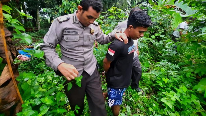 Pihak kepolisian saat membawa pelaku mencari pisau yang dibuangnya.