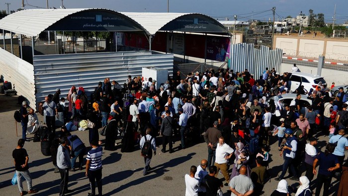 Potret Warga Palestina Padati Perbatasan Rafah-Mesir Saat Gaza Membara Palestinians with dual citizenship gather outside Rafah border crossing with Egypt in the hope of getting permission to leave Gaza, amid the ongoing Israeli-Palestinian conflict, in Rafah in the southern Gaza Strip October 16, 2023. REUTERS/Ibraheem Abu Mustafa