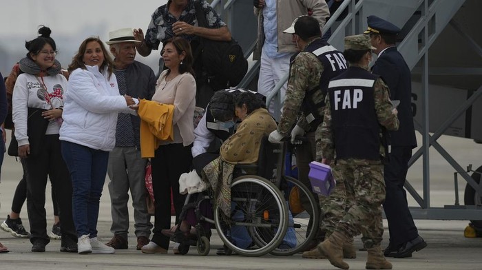 Peruvian President Diana Boluarte, left, leads Peruvians repatriated from Israel, down the stairway after landing in the presidential plane at the air force base in Callao, Peru, Sunday, Oct. 15, 2023. (AP Photo/Guadalupe Pardo)
