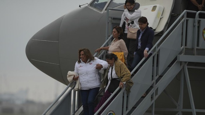 Peruvian President Diana Boluarte, left, leads Peruvians repatriated from Israel, down the stairway after landing in the presidential plane at the air force base in Callao, Peru, Sunday, Oct. 15, 2023. (AP Photo/Guadalupe Pardo)