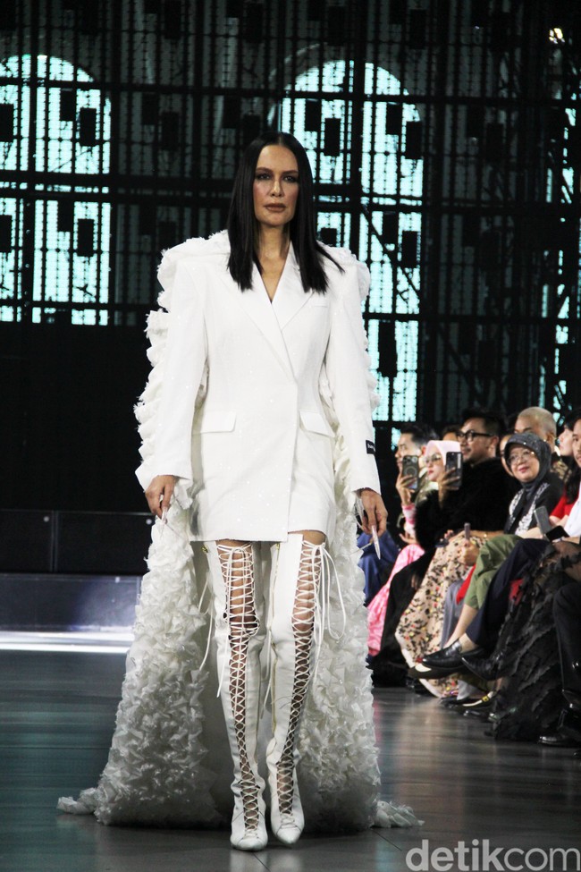 Busana tersebut dilengkapi semacam jubah dengan ekor panjang ruffle yang menjuntai hingga menyapu lantai. Kesan dramatis pun terpancar. (Foto: Abduh/detikcom)