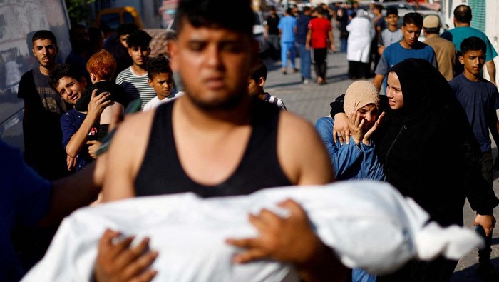 A man carries the body of a Palestinian child killed in Israeli strikes as mourners react, outside a hospital in Khan Younis in the southern Gaza Strip, October 17, 2023. REUTERS/Mohammed Salem     TPX IMAGES OF THE DAY