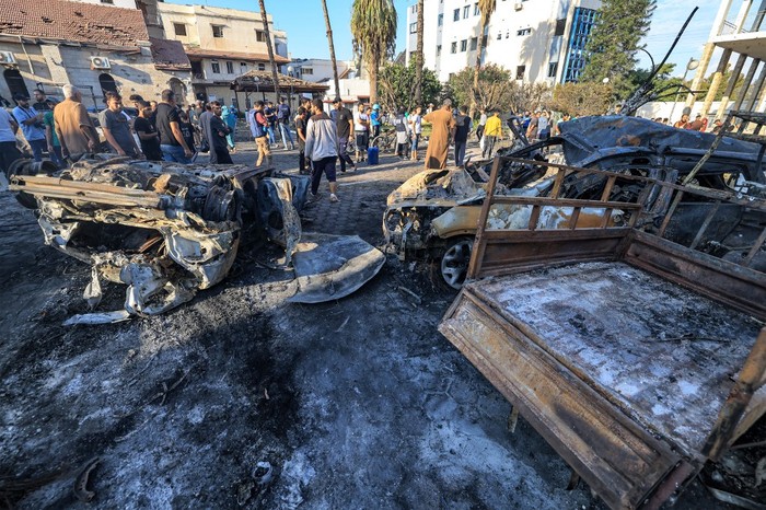 People search through debris outside the site of the Ahli Arab hospital in central Gaza on October 18, 2023 in the aftermath of an overnight blast there. A blast ripped through a hospital in war-torn Gaza killing hundreds of people late on October 17, sparking global condemnation and angry protests around the Muslim world.  Spokesman Hagari told a press briefing that at the time of the incident, the Israeli army was not conducting air operations near the hospital and the rockets that hit the building did not match theirs. (Photo by MAHMUD HAMS / AFP)