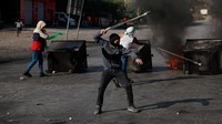 Warga Palestina menggunakan ketapel untuk melemparkan batu selama bentrokan dengan pasukan Israel di dekat Ramallah di Tepi Barat yang diduduki Israel, Rabu (18/10/2023).  