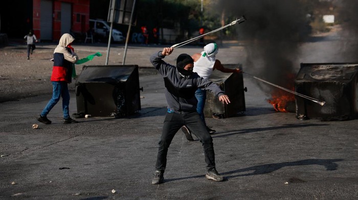 Palestinians hurl stones during clashes with Israeli forces near Ramallah in the Israeli-occupied West Bank October 18, 2023. REUTERS/Ammar Awad