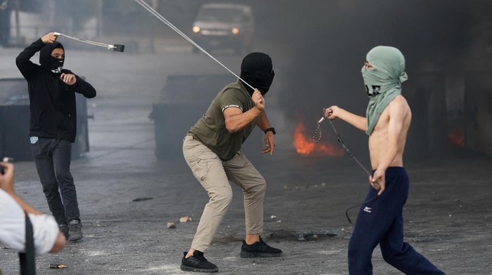 Palestinians hurl stones during clashes with Israeli forces near Ramallah in the Israeli-occupied West Bank October 18, 2023. REUTERS/Ammar Awad