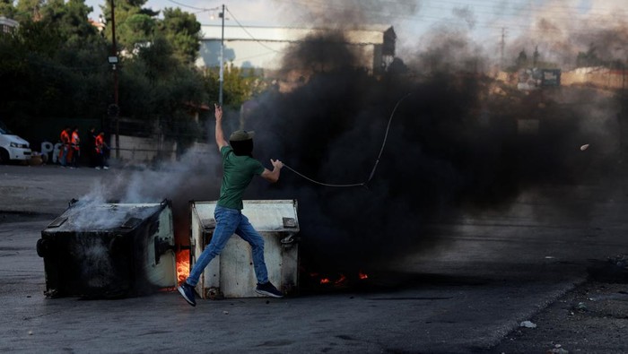 Palestinians hurl stones during clashes with Israeli forces near Ramallah in the Israeli-occupied West Bank October 18, 2023. REUTERS/Ammar Awad