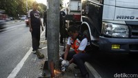Petugas Dishub memotong baut tiang papan penunjuk jalan sebelum dirobohkan.  