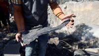 Warga menunjukkan serpihan rudal Israel di sekitar kawah. Sejauh ini, korban tewas akibat serangan Israel telah mencapai lebih dari 3.400 orang.   