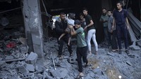 Warga Palestina juga membantu mengevakuasi korban luka dari bangunan yang hancur di Khan Younis, Jalur Gaza.  