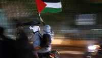 Para pengunjuk rasa berkendara sambil mengibarkan bendera Palestina. Massa aksi tidak hanya protes di kedubes Prancis, tapi juga di kedubes Inggris.