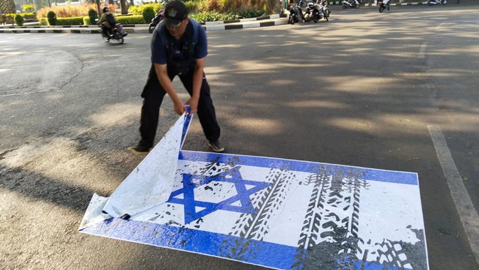 Sejumlah petugas Satpol PP Kota Malang mengelupas stiker bendera Israel yang ditempelkan di jalanan.