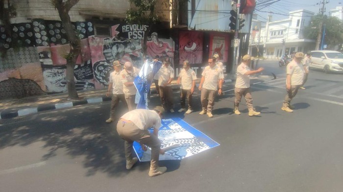 Sejumlah petugas Satpol PP Kota Malang mengelupas stiker bendera Israel yang ditempelkan di jalanan.