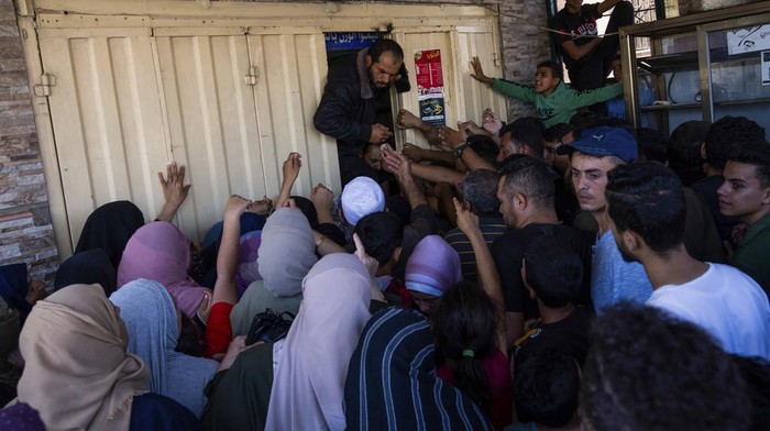 FILE - Palestinians crowding to buy bread from a bakery, in Khan Younis, Gaza Strip, Sunday, Oct, 15, 2023. Since the Israeli military decided to cut off the Gaza Strip's water and fuel and prevent aid convoys from entering, Palestinians in Gaza have sheltered with their families far from their homes and struggled to survive. It's a grueling routine — waiting hours for bread, trying to find water, soothing children during bombings. (AP Photo/Fatima Shbair, File)