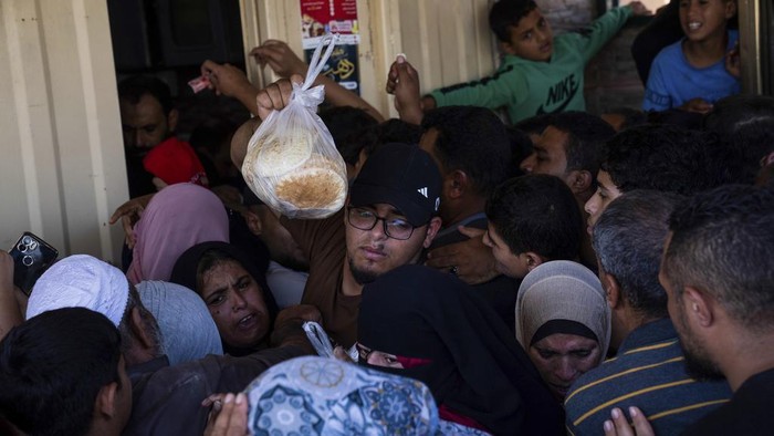 FILE - Palestinians crowding to buy bread from a bakery, in Khan Younis, Gaza Strip, Sunday, Oct, 15, 2023. Since the Israeli military decided to cut off the Gaza Strip's water and fuel and prevent aid convoys from entering, Palestinians in Gaza have sheltered with their families far from their homes and struggled to survive. It's a grueling routine — waiting hours for bread, trying to find water, soothing children during bombings. (AP Photo/Fatima Shbair, File)
