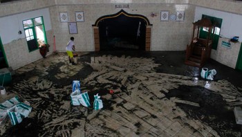 Indonesia sebagai negara kepulauan sudah merasakan dampak kenaikan permukaan air laut. Tampak pada foto ini, seorang pria membersihkan lumpur sisa gelombang pasang dari lantai masjid. Foto: CBS News