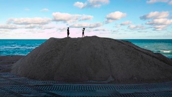 Orang-orang berdiri di atas gundukan pasir yang dibuang di pantai di Miami Beach, Florida, pada 16 Januari 2020. Puluhan truk mulai membuang ratusan ribu ton pasir di Pantai Miami sebagai bagian dari tindakan pemerintah AS untuk melindungi tujuan wisata Florida dari dampak perubahan iklim. Foto: CBS News