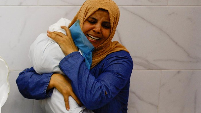 A woman embraces the body of a Palestinian child killed in Israeli strikes, at a hospital in Khan Younis in the southern Gaza Strip, October 17, 2023. REUTERS/Mohammed Salem
