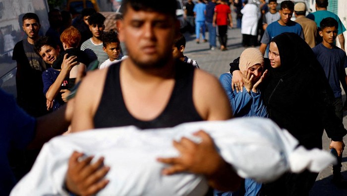 A woman embraces the body of a Palestinian child killed in Israeli strikes, at a hospital in Khan Younis in the southern Gaza Strip, October 17, 2023. REUTERS/Mohammed Salem