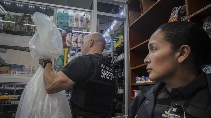 Law enforcement members of New York Sheriff's Joint Compliance Task Force (SJCTF) confiscate and bag illegal vaping products, during raid of a tobacco shop, Wednesday Sept. 27, 2023, in New York. Communities across the U.S. are confronting a new vaping problem: how to get rid of millions of disposable e-cigarettes that are considered hazardous waste. The devices contain nicotine, lithium and other materials that cannot be reused or recycled. (AP Photo/Bebeto Matthews)