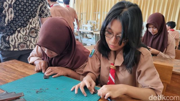 Sejumlah siswa SMKN 12 Surabaya memanfaatkan limbah sepatu kulit menjadi merchandise.