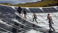 Karyawan produsen dan pemasok listrik Swiss CKW memasang panel surya di parabola milik Leuk Teleport and Data Center di Leuk, Swiss, Rabu (18/10/2023).