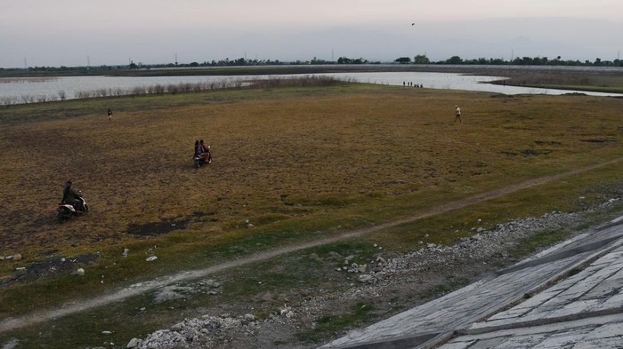 Waduk Notopuro di Madiun mengering Warga mengendarai sepeda motor melintasi areal dasar Waduk Notopuro yang airnya menyusut di Kabupaten Madiun, Jawa Timur, Kamis (19/10/2023). Waduk yang memiliki daerah irigasi seluas 2.689 hektare sawah tersebut tinggal menyisakan sedikit air hingga sebagian besar dasar waduk mengering akibat musim kemarau. ANTARA FOTO/Siswowidodo/aww.