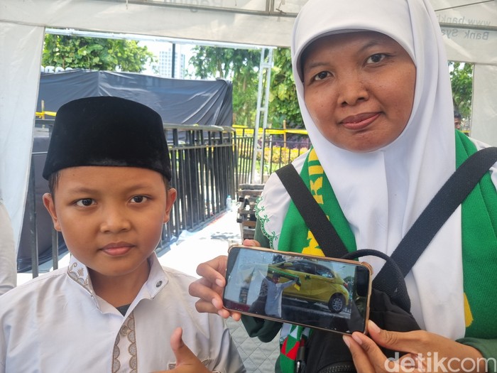 Adit dan ibunya berfoto di mobil kuning yang sekarang menjadi miliknya