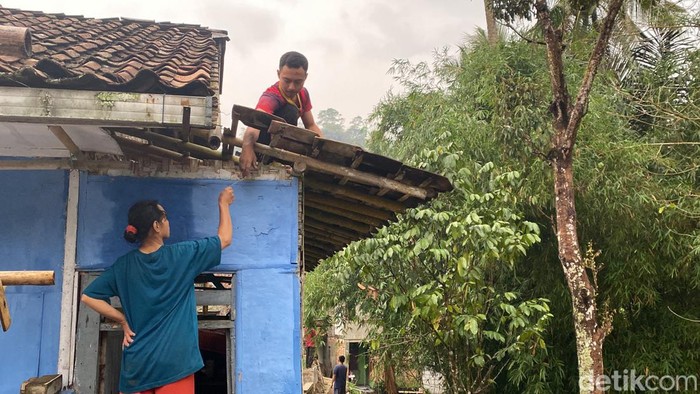 Warga tengah memperbaiki atap rumah yang rusak usai diterjang angin puting beliung.