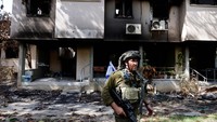 Seorang tentara Israel berjaga di depan sebuah rumah yang rusak diserang Hamas. 