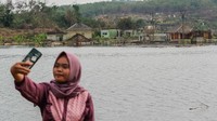 Pengunjung berswafoto dengan latar belakang kampung yang mulai tenggelam di Kampung Sinday, Lebak, Banten, Minggu (22/10/2023). 