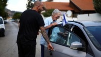 Seorang pria membantu ayahnya yang sudah lanjut usia masuk ke dalam mobil agar bisa dievakuasi dari Kiryat Shmona. 