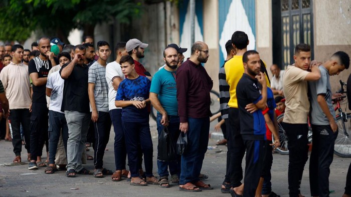 Potret Warga Gaza Antre Beli Roti Palestinians queue as they wait to buy bread from a bakery, amid shortages of food supplies and fuel, as the conflict between Israel and Palestinian Islamist group Hamas continues, in Khan Younis in the southern Gaza Strip October 22, 2023. REUTERS/Mohammed Salem