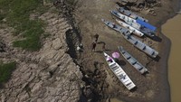 Warga terlihat di samping perahu mereka, di hamparan kering Sungai Solimoes. 