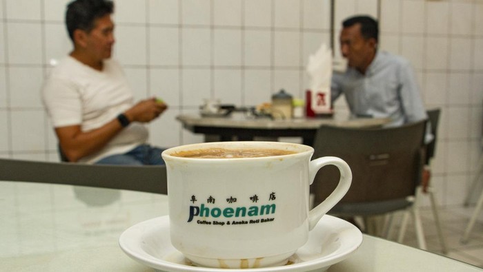 Warkop Legendaris Ini Jadi Tempat Nongkrong Bapak-bapak di Makassar Pengunjung berbincang sambil menikmati minuman kopi di Warung Kopi (Warkop) Phoenam, Makassar, Sulawesi Selatan, Jumat (6/10/2023). Warkop legendaris tersebut didirikan pada 1946 oleh Liong Thay Hiong bersama kerabat dekatnya dan saat ini dikelola oleh generasi ketiga dengan tetap mempertahankan gaya penyajian secara tradisional. ANTARA FOTO/Arnas Padda/tom.