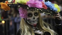 Seorang wanita berpakaian seperti Catrina dan berwajah tengkorak saat menjelang perayaan Hari Kematian.