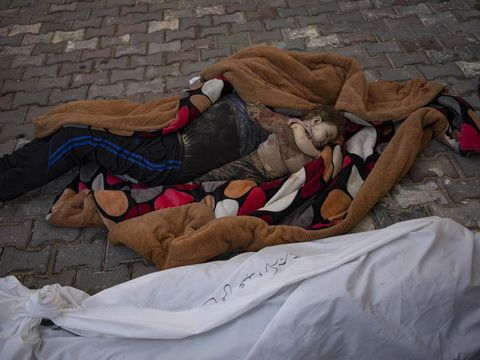 Jenazah seorang ayah dan anaknya yang tewas dalam pemboman Israel di Jalur Gaza, tergeletak di depan kamar mayat Rumah Sakit Al-Aqsa di Deir Al-Balah, Minggu, 22 Oktober 2023. ( AP Photo/Fatima Shbair)