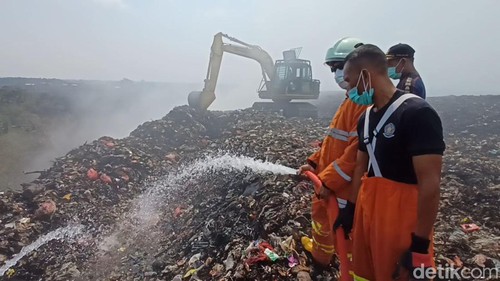 Petugas pemadam kebakaran dari Tabanan dan Badung mengisi air pada kubangan yang dibuat di bukit sampah TPA Mandung untuk mendinginkan gas metan dan memadamkan bara api, Minggu (23/10/2023). (chairul amri simabur/detikBali)