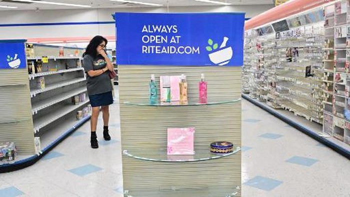 A woman browses through what items remain on near empty shelves at a Rite Aid store in Alhambra, California, on October 18, 2023, that is due for closure next Monday. The US pharmacy chain this week filed for Chapter 11 and plans to close almost 100 stores nationwide, including 31 in California, as part of its restructuring plan after filing for bankruptcy. (Photo by Frederic J. BROWN / AFP)