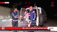 Yocheved Lifshitz tampak dipeluk saat keluar dari dalam ambulans. Al Qahera News/Handout via Reuters.