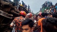 Tim penyelamat sedang melakukan evakuasi penumpang yang terperangkap di bawah gerbong yang terbalik.  
