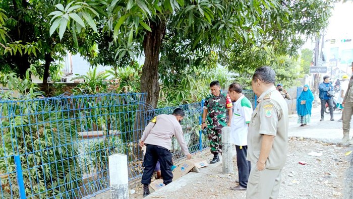 Polisi mengecek jasad pria berkaus putih di sela got Karawang