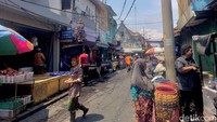 Potret seorang wanita sedang manggul eber diatas kepalanya yang berisikan ikan.