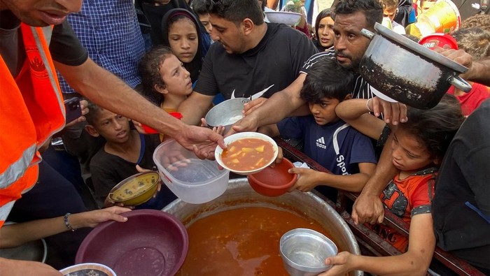 Potret Pengungsi Palestina Antre Bantuan Makanan Warga Palestina yang mengungsi akibat serangan Israel ke Jalur Gaza menerima bantuan makanan, Senin (2310) waktu setempat.