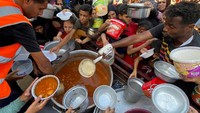 Para pengungsi mengantre makanan dengan membawa wadah berupa mangkok hingga panci.  