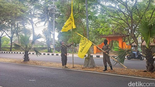 Satpol PP Kabupaten Karangasem saat menurunkan bendera dari partai Golkar yang terpasang di Jalan Raya Veteran.