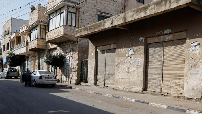 Senior Hamas Tewas di Penjara Israel, Toko-toko di Tubas Tutup A man sits outside a closed shop during a general strike over the death of Palestinian prisoner Omar Daraghmeh in Israeli jail, in Tubas, in the Israeli-occupied West Bank, October 24, 2023. REUTERS/Raneen Sawafta