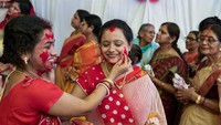 Para wanita Hindu diberikan olesan warna merah terang di wajahnya.  