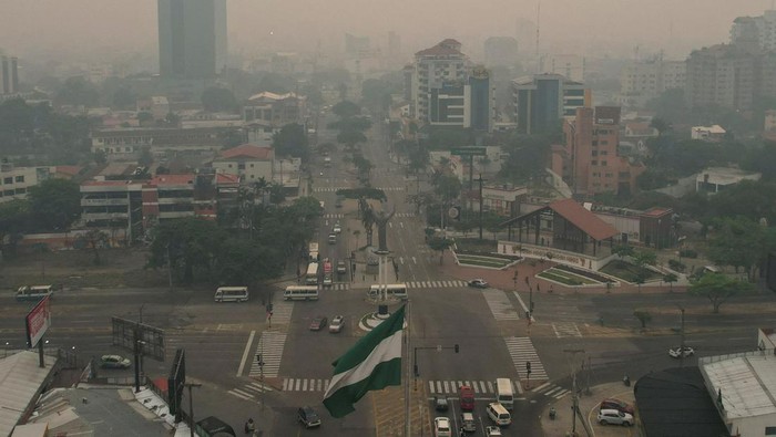 People walk and drive through smoke caused by wildfires in the area, which prompted the local government to issue a red sanitary alert due to the heavy pollution, in Santa Cruz, Bolivia October 24, 2023. REUTERS/Claudia Belaunde NO RESALES. NO ARCHIVES